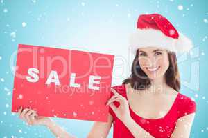 Composite image of festive brunette with sale sign
