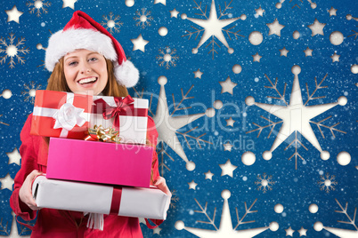 Composite image of festive redhead holding pile of gifts