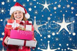 Composite image of festive redhead holding pile of gifts