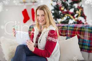 Composite image of cute blonde sitting on couch holding credit c
