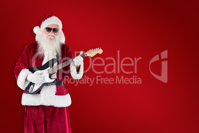 Composite image of santa claus plays guitar with sunglasses