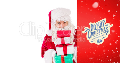 Composite image of smiling santa holding pile of gifts