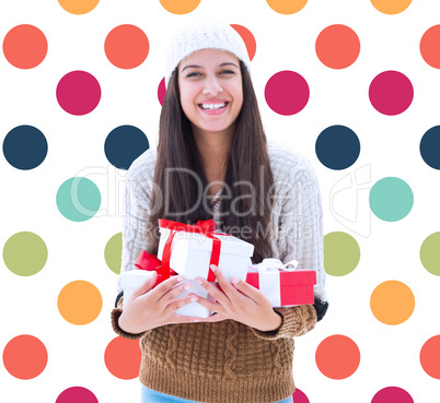 Composite image of festive brunette holding gifts