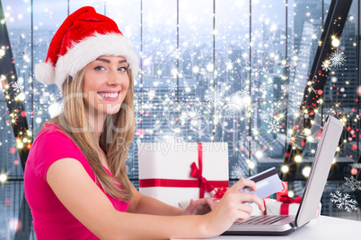 Composite image of festive blonde shopping online with laptop