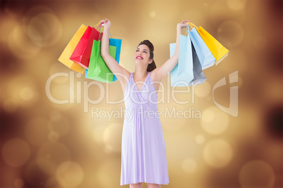 Composite image of smiling brunette showing shopping bags