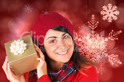 Composite image of pretty brunette in hat holding a gift