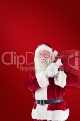 Composite image of santa carries his red bag and smiles