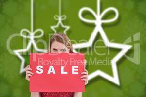 Composite image of cute blonde showing a red sale poster