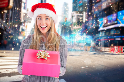 Composite image of festive blonde holding christmas gift