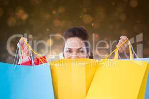 Composite image of happy brunette opening shopping bags