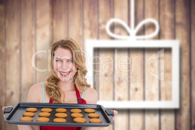 Composite image of smiling woman showing hot cookies