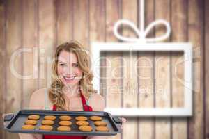 Composite image of smiling woman showing hot cookies