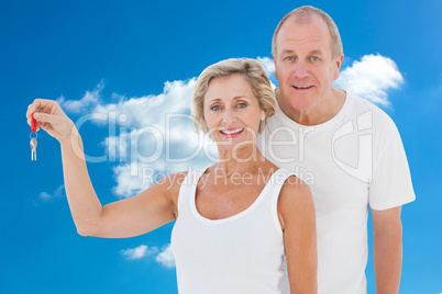 Composite image of mature couple smiling at camera with new hous