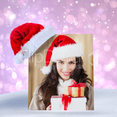 Composite image of festive brunette in santa hat holding gifts