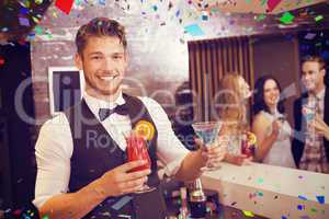 Composite image of handsome barman smiling at camera holding coc