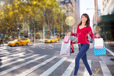 Composite image of excited brunette with shopping bags