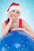 Composite image of festive fit brunette leaning on exercise ball