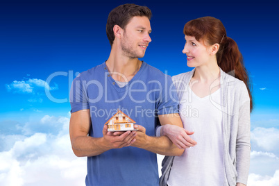 Composite image of couple holding a model house