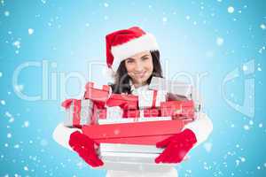 Composite image of smiling brunette in santa hat holding stack o