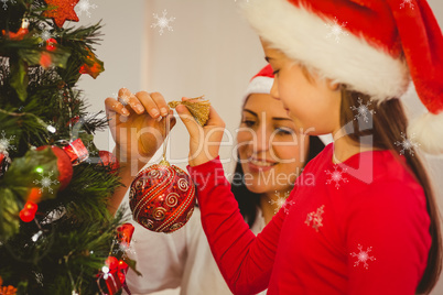 Composite image of mother and daughter hanging christmas decorat