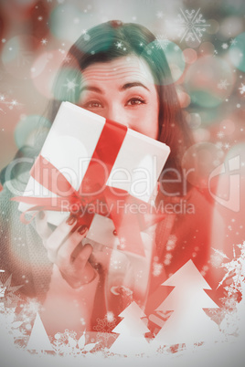 Composite image of brunette showing gift on the couch at christm