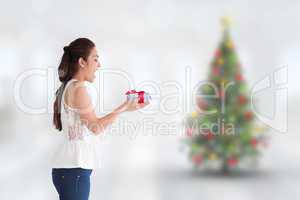 Composite image of surprised brunette holding a present