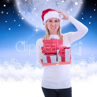 Composite image of stressed blonde in santa hat holding gifts