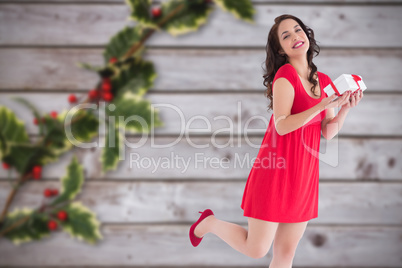 Composite image of stylish brunette in red dress holding gift