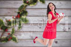 Composite image of stylish brunette in red dress holding gift