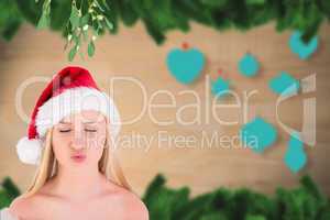Composite image of festive cute blonde under mistletoe