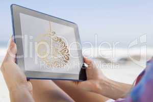 Composite image of woman sitting on beach in deck chair using ta