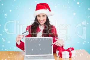 Composite image of festive brunette shopping online