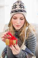 Composite image of pretty woman sitting on a couch while opening a gift box