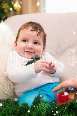 Composite image of cute baby boy on the couch at christmas