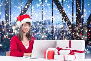 Composite image of festive brunette shopping online with laptop