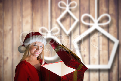 Composite image of festive blonde holding a gift