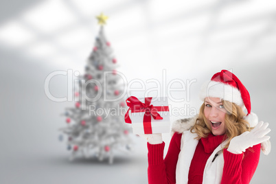Composite image of excited blonde in santa hat holding gift Composite image of excited blonde in santa hat holding gift