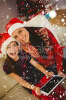 Composite image of festive mother and daughter using tablet pc