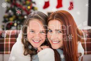 Composite image of festive mother and daughter on the couch