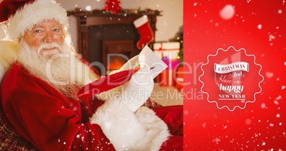 Composite image of smiling santa writing list with a quill