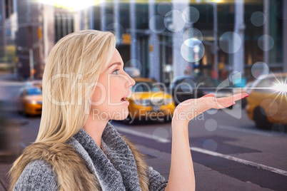 Composite image of blonde in winter clothes with hand out