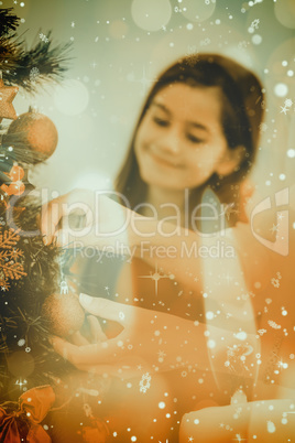 Composite image of woman hanging christmas decorations on tree