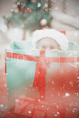 Composite image of cute little girl sitting in giant christmas g