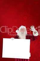 Composite image of santa holds a sign and is waving