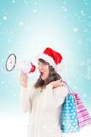 Composite image of festive brunette holding megaphone and bags