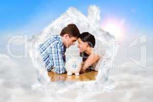 Composite image of young couple lying on floor smiling with pigg
