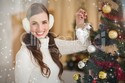 Composite image of smiling brunette holding heart near a christm