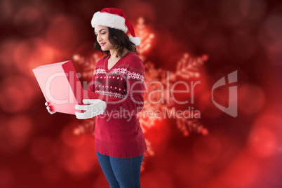 Composite image of festive brunette in winter clothes opening gi