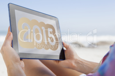 Composite image of woman sitting on beach in deck chair using ta