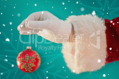 Composite image of santas hand is holding a christmas bulb